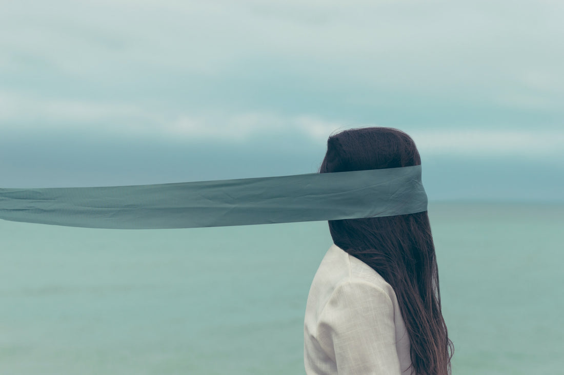 Photo of a person with long hair and a ribbon over their eyes. It's not clear which way the person is facing. Text says: Exploring the Dark Side: Embracing Shadow Work in Witchcraft